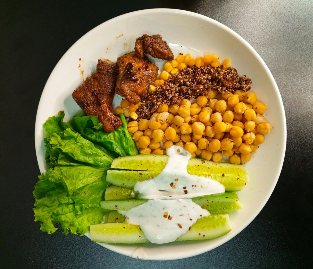 وجبة صحية متوازنة تحتوي على خضار وخس وخيار مع الحمص والكينوا وقطع دجاج للرجيم